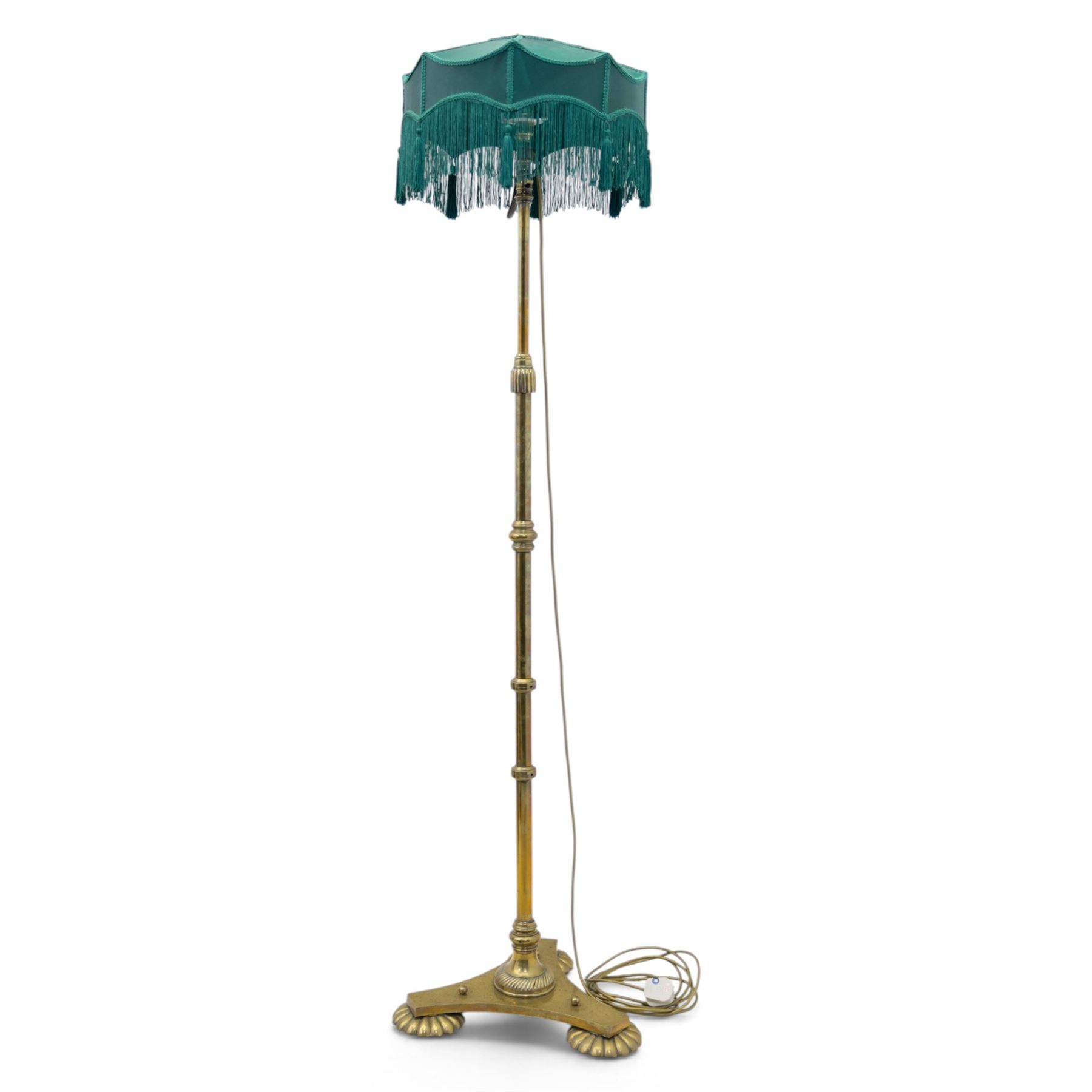 Art Deco brass standard lamp, telescopic column with level action, ring turned collars, raised on a shaped tri-form base with fluted pad feet, complete with green fabric fringed shade