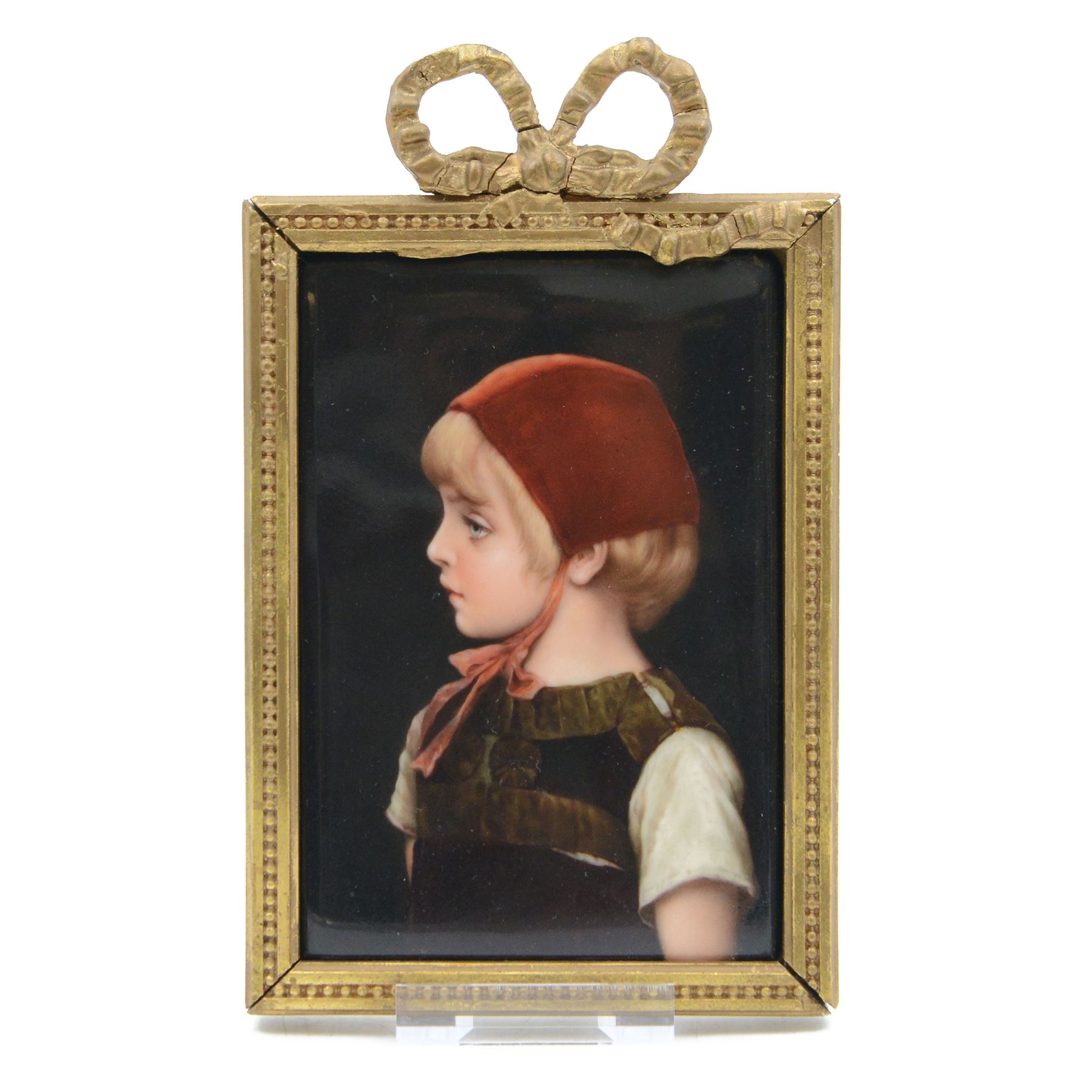 Late 19th/early 20th century German hand painted porcelain plaque, depicting a young girl in a red bonnet, after a painting by Gabriel Schachinger, within a beaded gilt frame with bow surmount, bearing paper label for Kunstinstitut fur Porzellan-Malerei Merkel-Heine Wiesbaden verso, and further paper label indistinctly inscribed '286 [...] Schachinger', also impressed 107, not including bow 16cm x 11.5cm
