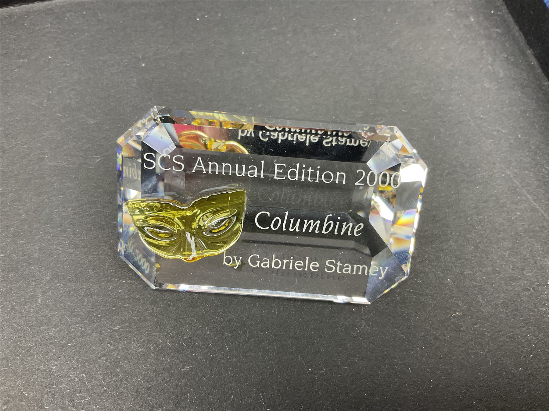 Swarovski Crystal Masquerade trilogy; 1999 Masquerade Pierrot, 2000 Columbine, 2001 Harlequin all with accompanying plaque, stand and original box, together with a glass display case with mirrored back and sides 