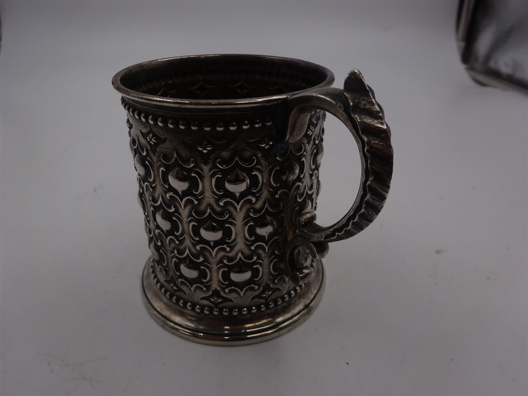 Victorian silver christening mug, with repousse and chased scroll and bead decoration, lozenge shaped cartouche engraved with monogrammed initials and acanthus capped C scroll handle, hallmarked Robert Hennell III, London 1861, H9.3cm