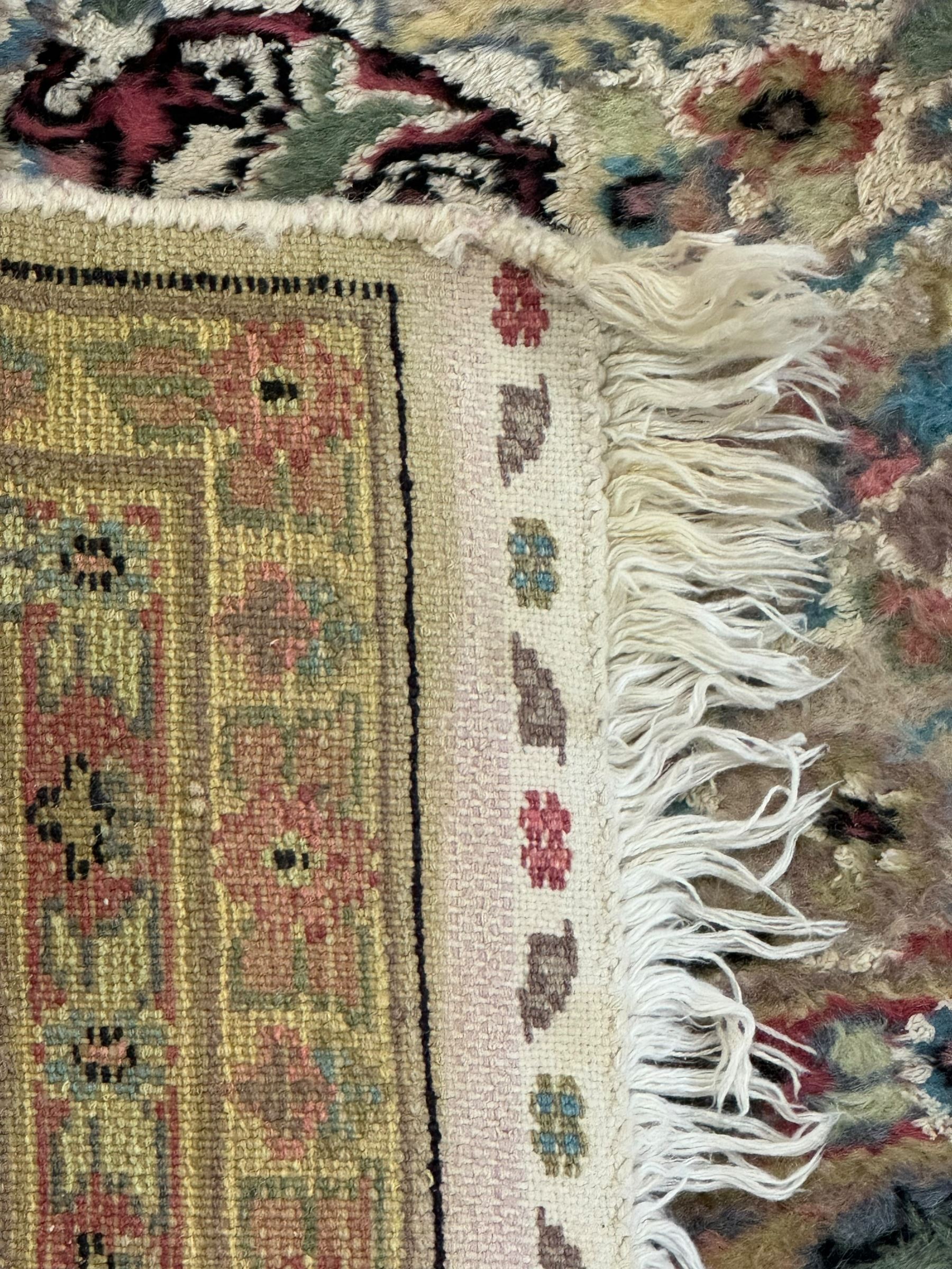 Persian design ivory ground rug, overall floral design with shaped central medallion, the main border decorated with trailing flower head pattern, within guard stipes 