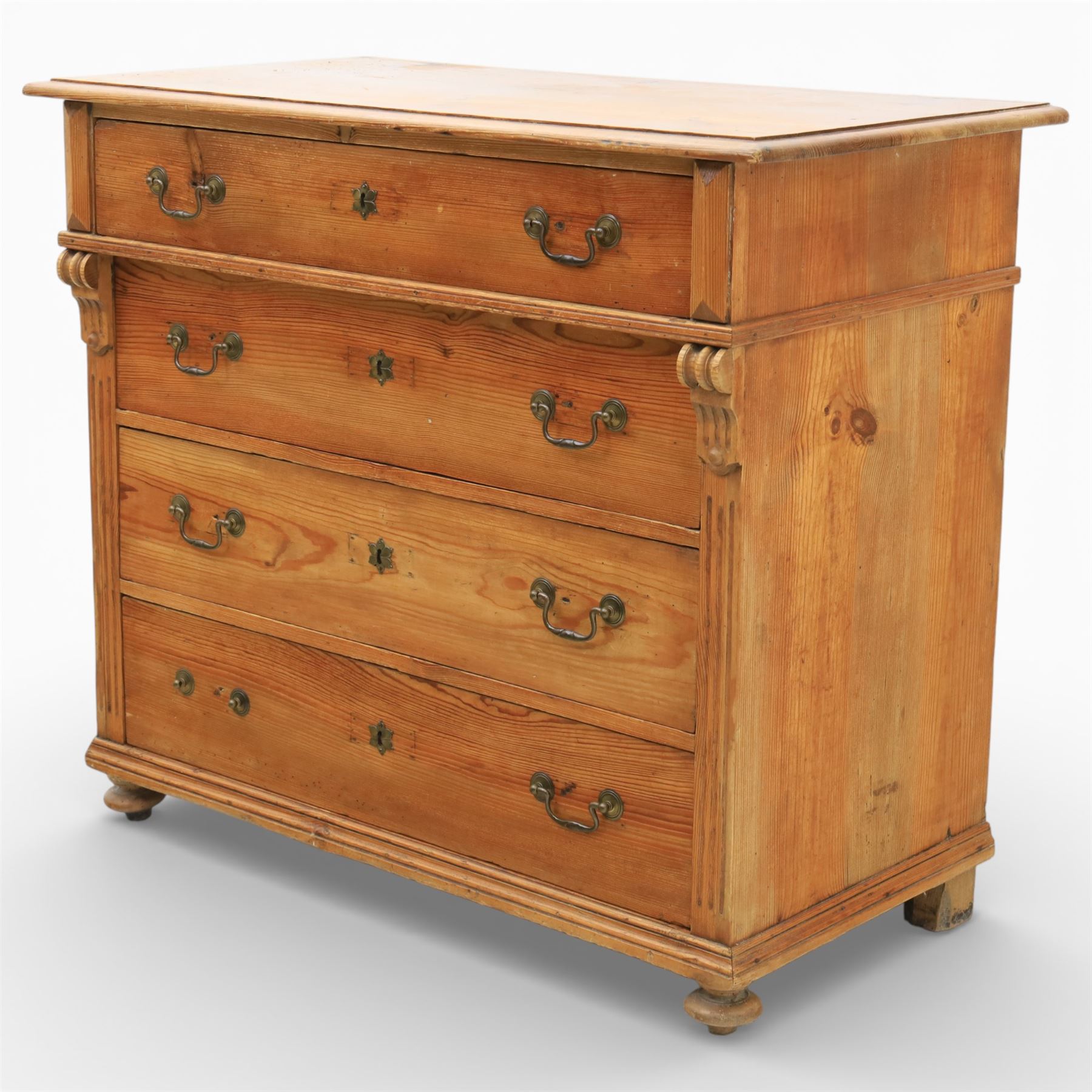 Late Victorian pine chest of drawers, the moulded top above four long drawers with brass drop handles and flower head escutcheons, flanked by pilasters, upon four turned compressed bun feet, 89cm x 103cm x 54cm