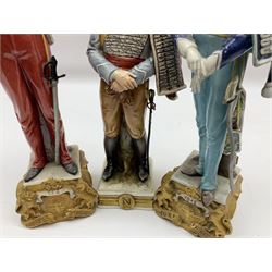 Group of seven Capodimonte figures of soldiers, to include four Bruno-Merli examples including Officer of the 12th Lancers 1820 and Captain of the 18th Hussars 1815, both raised upon ornate gilt plinths bearing British monarch motto in Latin 'Dieu et mon droit', and three further similar, all with crowned N mark beneath, tallest H32cm