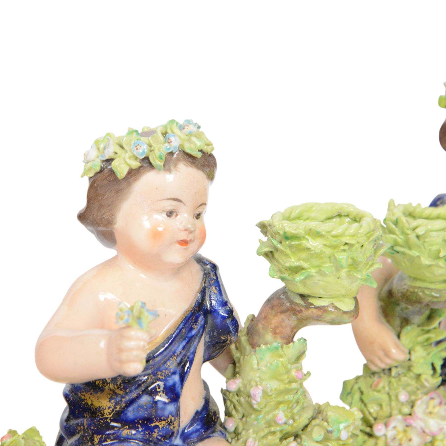Pair of 19th century Stevenson and Hancock Derby figural chambersticks, each modelled as a seated cherub with arm around foliate encrusted sconce, marked beneath, H18cm