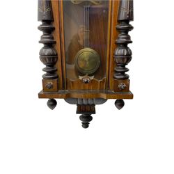 German - late 19th century mahogany and ebonised 8-day wall clock, with a shaped pediment, applied carvings and finials, fully glazed door with visible gridiron pendulum flanked by turned half columns , curved base with finials below, two part enamel dial with Roman numerals and pierced steel hands, count wheel striking movement sounding the hours and half hours on a coiled gong. With key. 