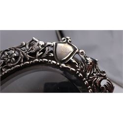 Continental silver miniature dressing table/wall mirror, of oval form with bevelled mirror plate, surrounded by a bead and dart rim, with pierced scrolling floral border with a standing cavalier to either side and the bust of a cavalier to the base, H17.7cm