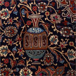 North East Persian Meshed hand-knotted carpet, deep navy field with central complex medallion and densely decorated scrolling floral sprays and palmettes, incorporating cartouche motifs enclosed by a broad tan and dark blue border ornamented by stylized vases flanked by multiple guard stripes, signed 'Amal-e Haji translates as the Work of Haji', with cotton fringe ends 