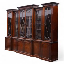 Large Georgian mahogany library bookcase, projecting moulded cornice with row of globular mounts, adjustable shelving enclosed by six astragal glazed doors, fitted with two slides and six panelled cupboard doors, two banks of five drawers, on moulded plinth base; together with two pairs of associated astragal glazed doors in mahogany, from the same property (W55.5cm x H168cm & W48cm x 168cm)