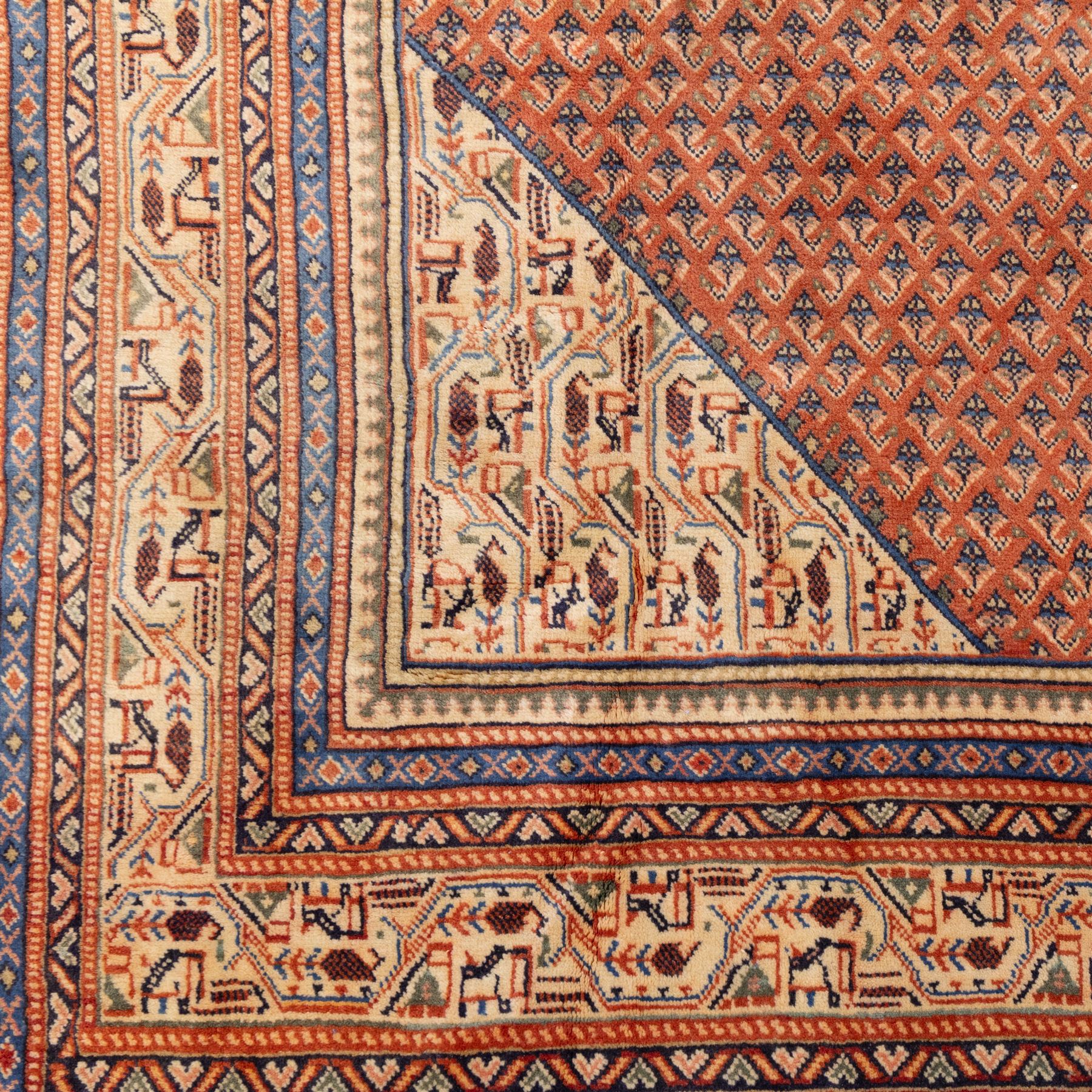 North West Persian Boteh-Mir hand-knotted rug, madder red field decorated with an all-over lattice of small boteh motifs and a central stepped lozenge medallion with repeating stylized boteh and geometric devices, spandrels similarly worked, with multiple narrow borders of floral and geometric bands, in tones of madder red, indigo blue, ivory, and soft green, with cotton fringe ends 