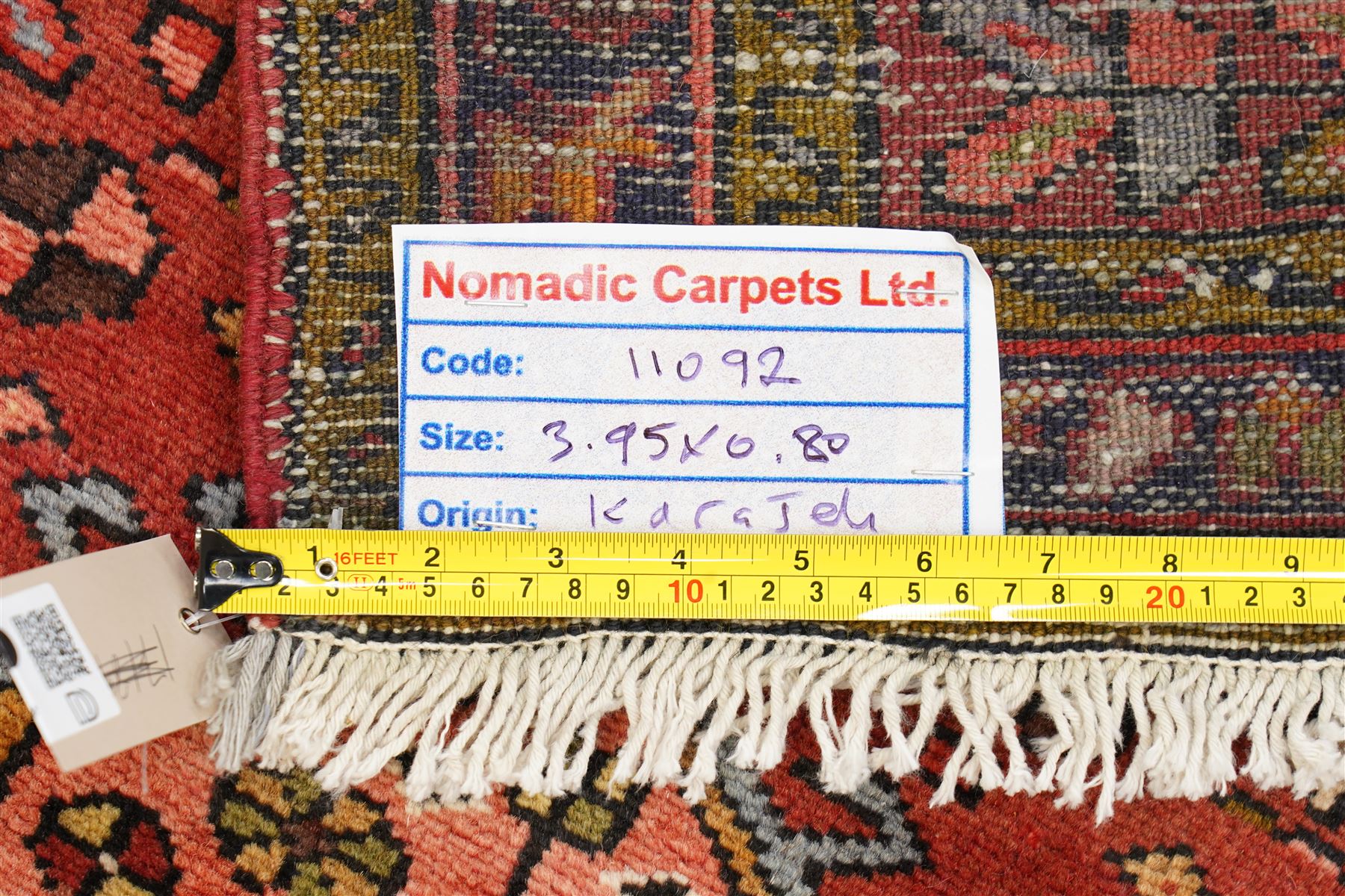 North West Persian Karajeh hand-knotted runner, madder red field with a series of shaped hexagonal medallions and cruciform motifs each enclosing geometric rosette devices linked by angular vine elements, field populated with stylized tribal ornaments, within narrow multiple borders decorated with repeating angular motifs framed by guard stripes of geometric devices, with cotton fringe ends  