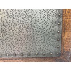 Arts and Crafts oak stand by Arthur Simpson of Kendal, of rectangular form with central hammered pewter panel, surrounded by a border with carved foliate corners, upon two bar supports, bearing label detailed 