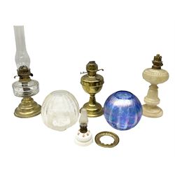 Four oil lamps to include brass example with clear glass reservoir, another brass example, opaque glass example moulded with flowers, miniature example with encrusted flowers etc, together with clear shade etched with cherubs, blue iridescent example etc