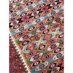 Turkaman red ground rug, the field divided into horizontal rows and decorated with geometric motifs, intricately pattern borders and end panels