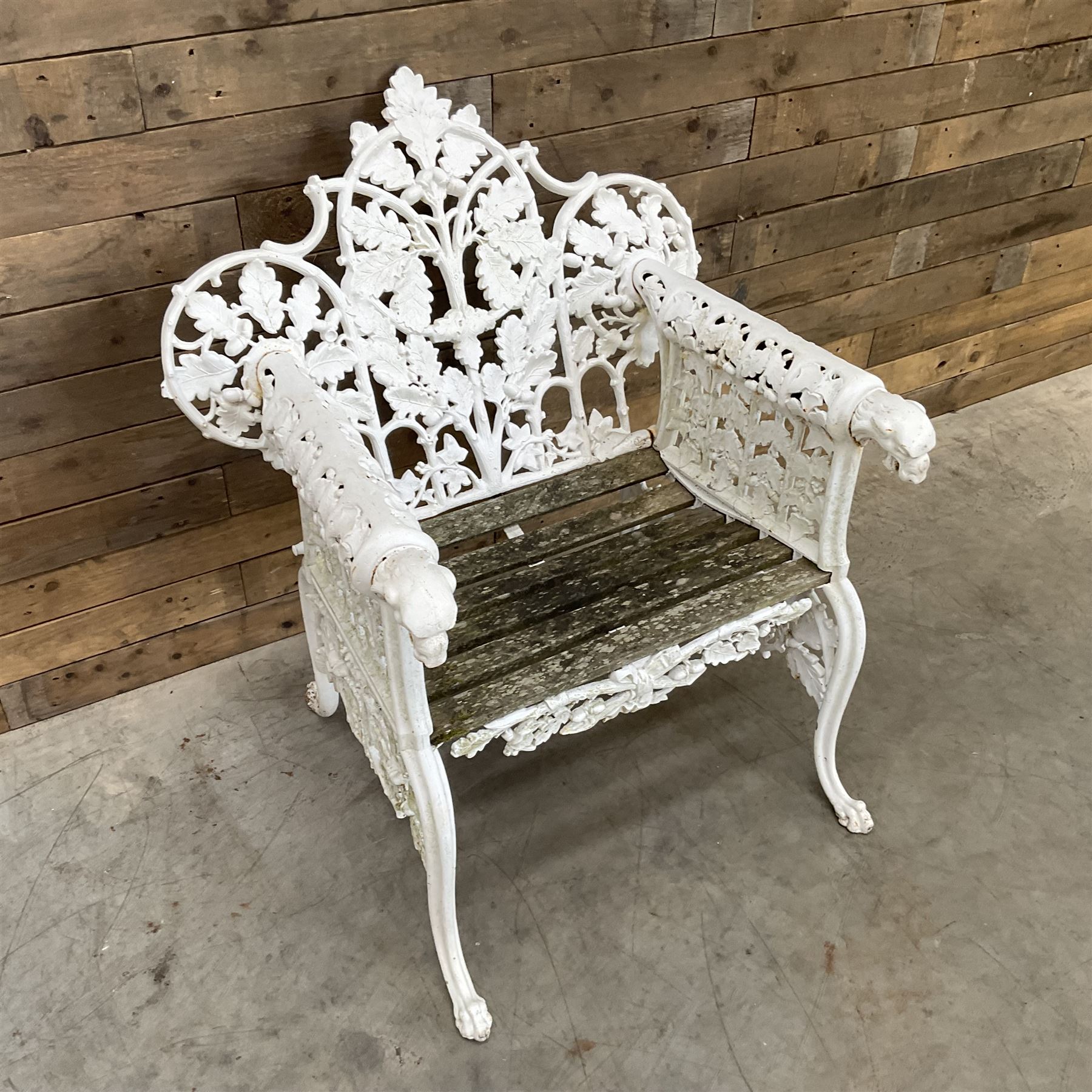 20th century Coalbrookdale design cast iron oak leaf and acorn armchair, white painted cast iron frame with slatted wooden seat, the pierced and shaped back decorated with scrolling oak branches and leafage, flanked by dog mask arm terminals over cabriole supports with paw feet