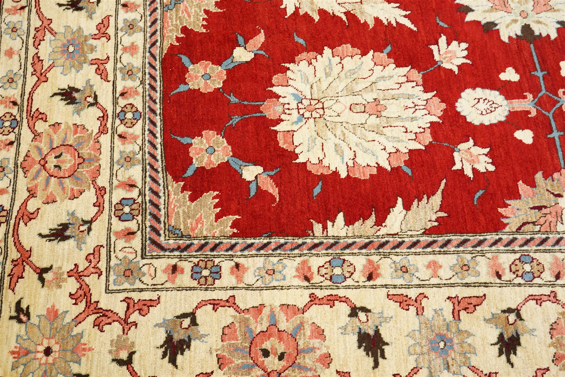 West Persian Sarough hand-knotted carpet, rich madder red field, decorated with stylized palmettes angular vinery and floral sprays within multiple borders of ivory ground and scrolling foliate decoration, with cotton fringe ends 