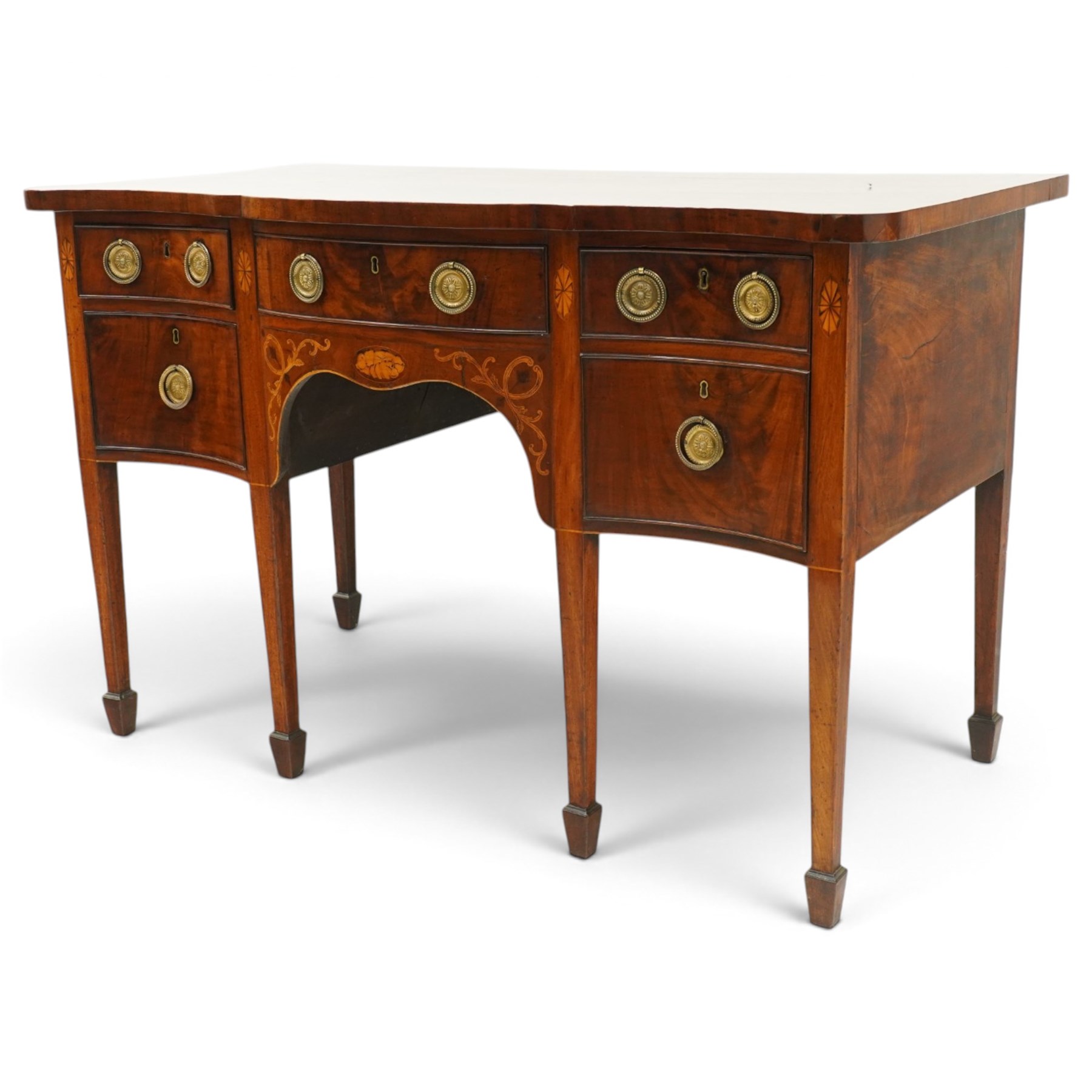 George III inlaid mahogany serpentine sideboard, the shaped top with crossbanding and satinwood stringing, fitted with central bow-front cock-beaded frieze drawer over a shaped apron inlaid with paterae, shell motifs and scrolling foliage, flanked by a deep right-hand drawer and two drawers to the left, raised on square tapering supports with spade feet