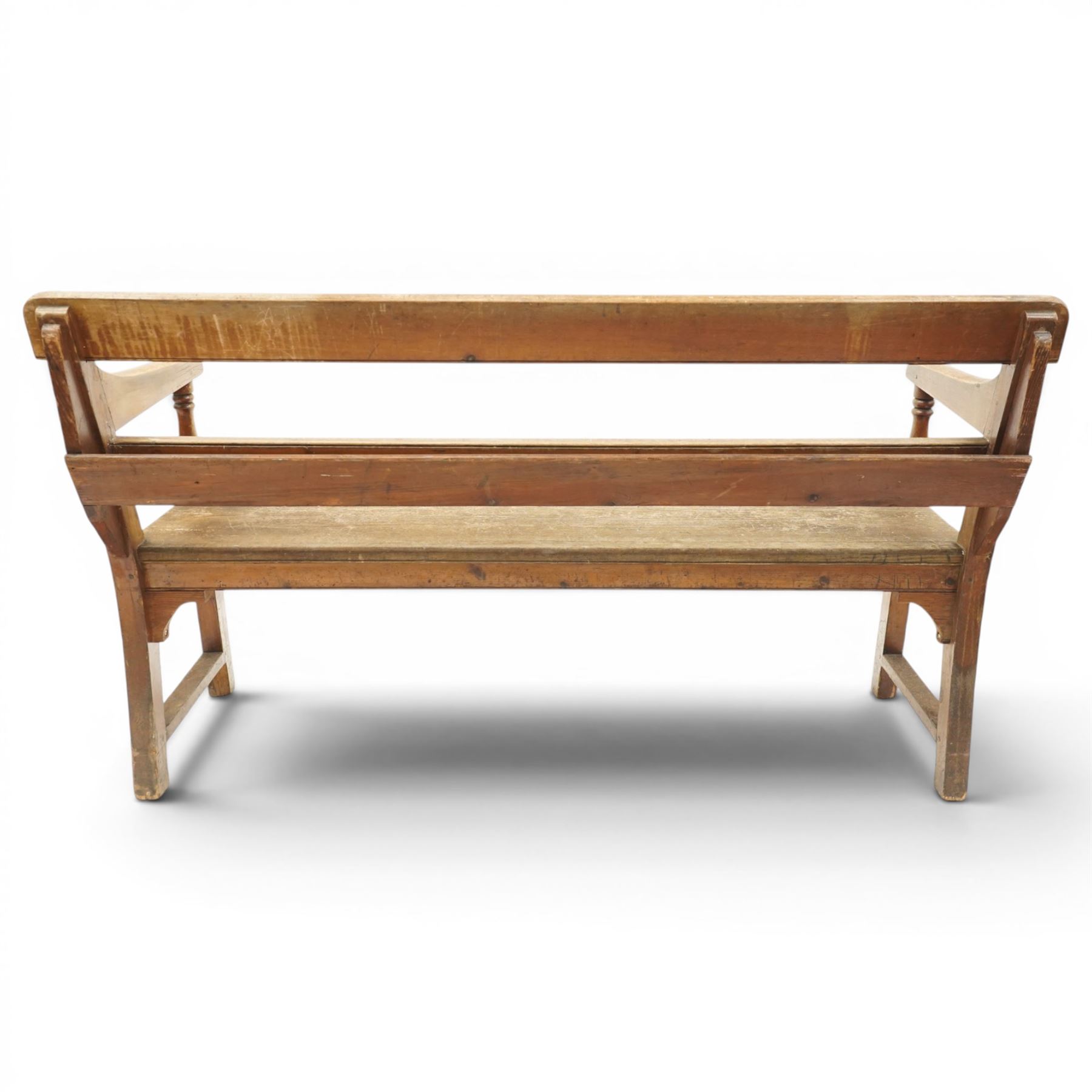 Early 20th century pine chapel bench, with moulded plank back rail over plain rail, with book storage to the back, open shaped end supports with curved arms, turned front uprights, plank seats, square legs united by low stretchers