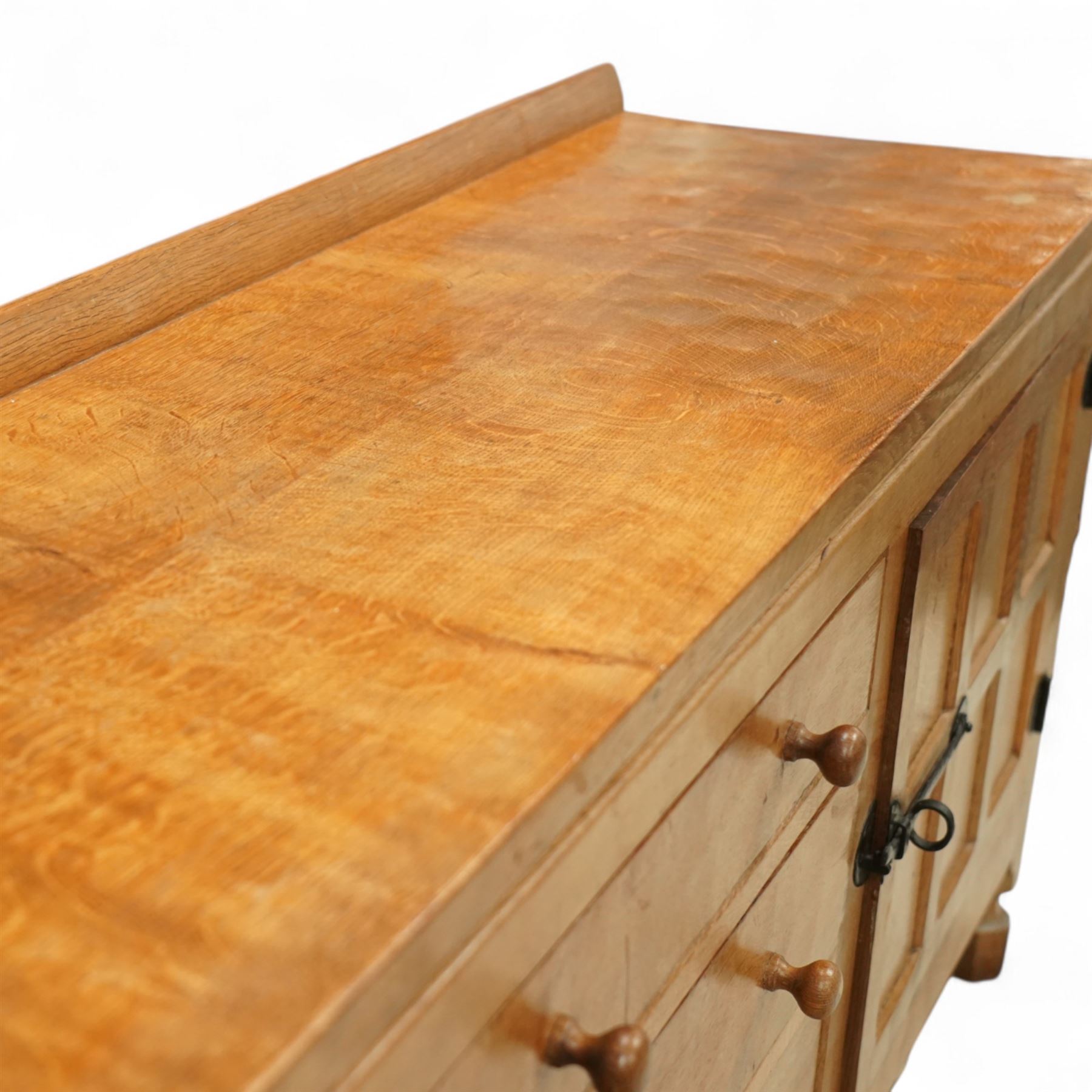 Mouseman - oak sideboard rectangular adzed top with raised back over three central drawers and two flanking cupboards, enclosed by panelled doors with wrought metal fixtures, the canted upright carved with mouse signature, on octagonal feet, by the workshop of Robert Thompson, Kilburn