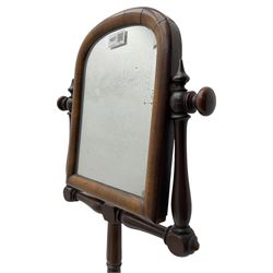 Early Victorian mahogany shaving mirror, arched frame with plain mirror plate on turned horns and supports, adjustable height mechanism on turned stem, circular platform base with four extending block feet carved with scrolled foliage 