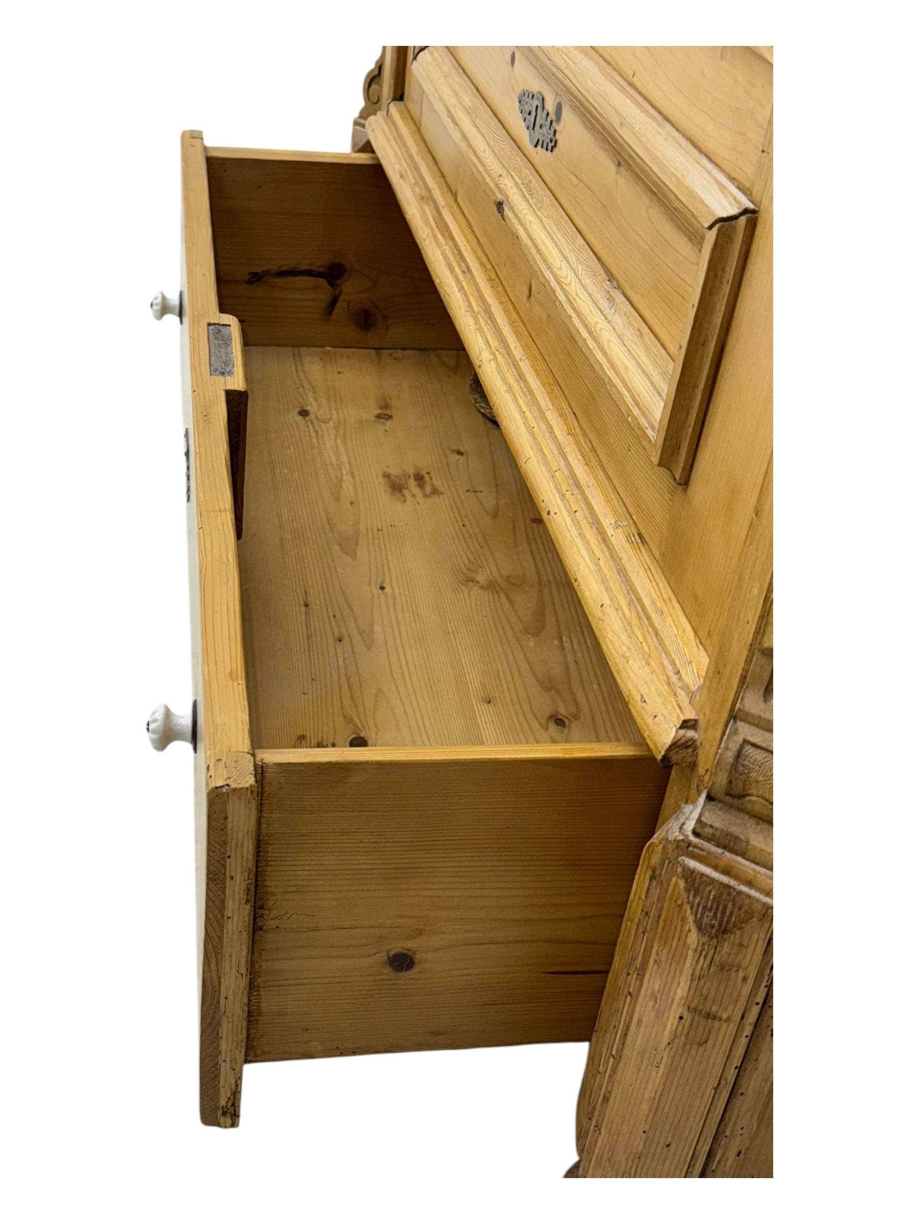 Late 19th century Continental pine vitrine, shaped and moulded arched cornice over a single glazed door enclosing adjustable shelves, flanked by carved pilasters with foliate and geometric motifs, fitted with single moulded drawer, raised on compressed bun feet