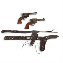 Two replica colts, each with a leather holster 