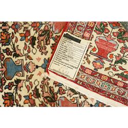 Iranian Persian style rug, repeated stylised vase and floral motifs arranged symmetrically across a ivory field, framed by red main border