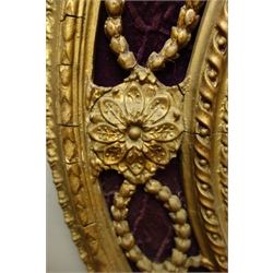 Pair 19th century ornate giltwood and gesso oval girandoles, ribbon moulded pediment with scrolls and flower heads, oval bevelled mirror plate surmounted by trailing foliage on purple velvet, three scones, 48cm x 102cm  