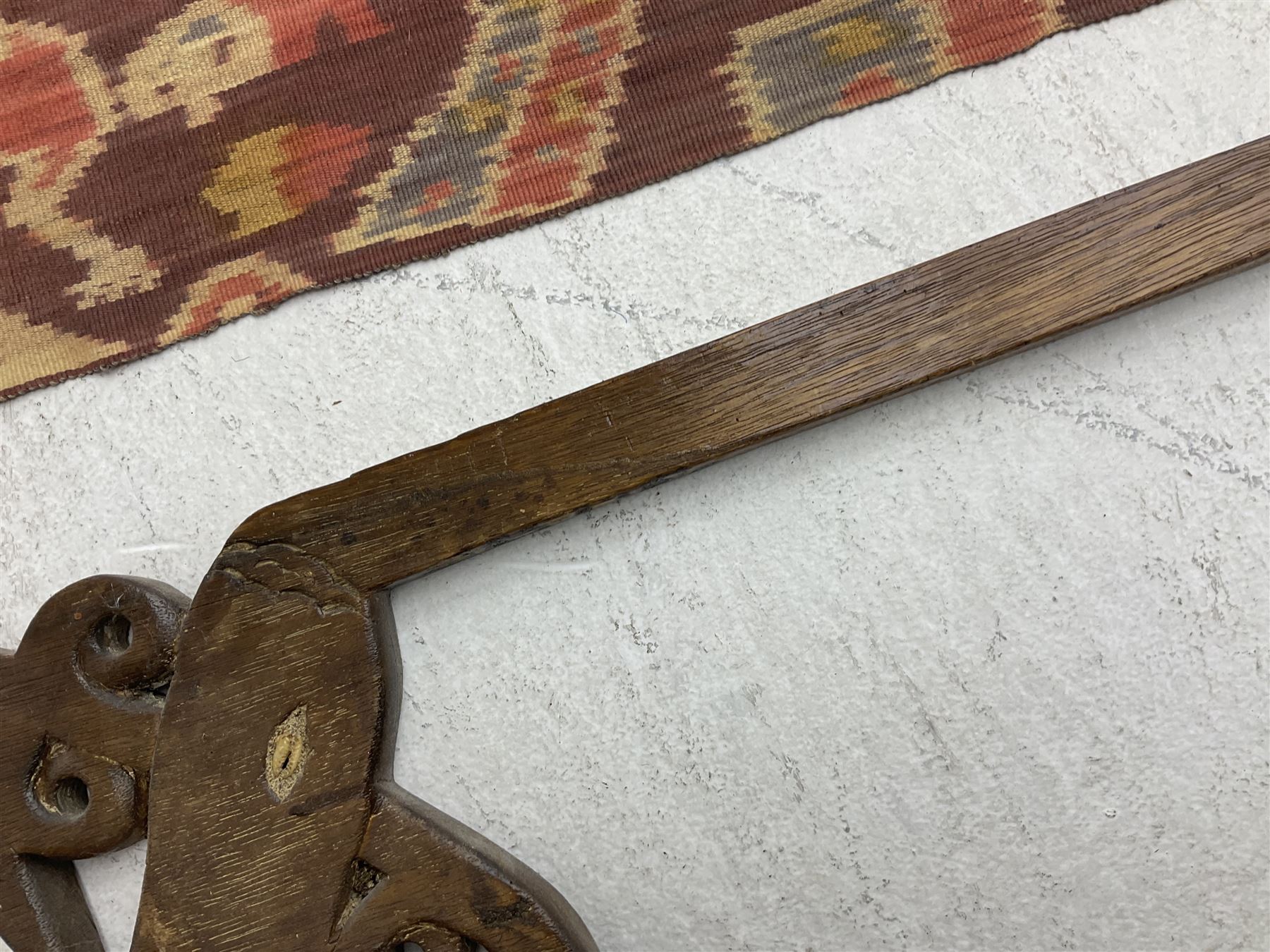 Ikat Man’s Cloth (Hinggi Kombu), East Sumba, Indonesia, woven in red, blue and yellow-brown warp ikat, constructed of two mirroring long panels, the motifs arranged in four bands depicting warrior figures astride rearing horses, high-ranking figures and guardians within geometric borders, on carved wooden wall hanger, L295cm
