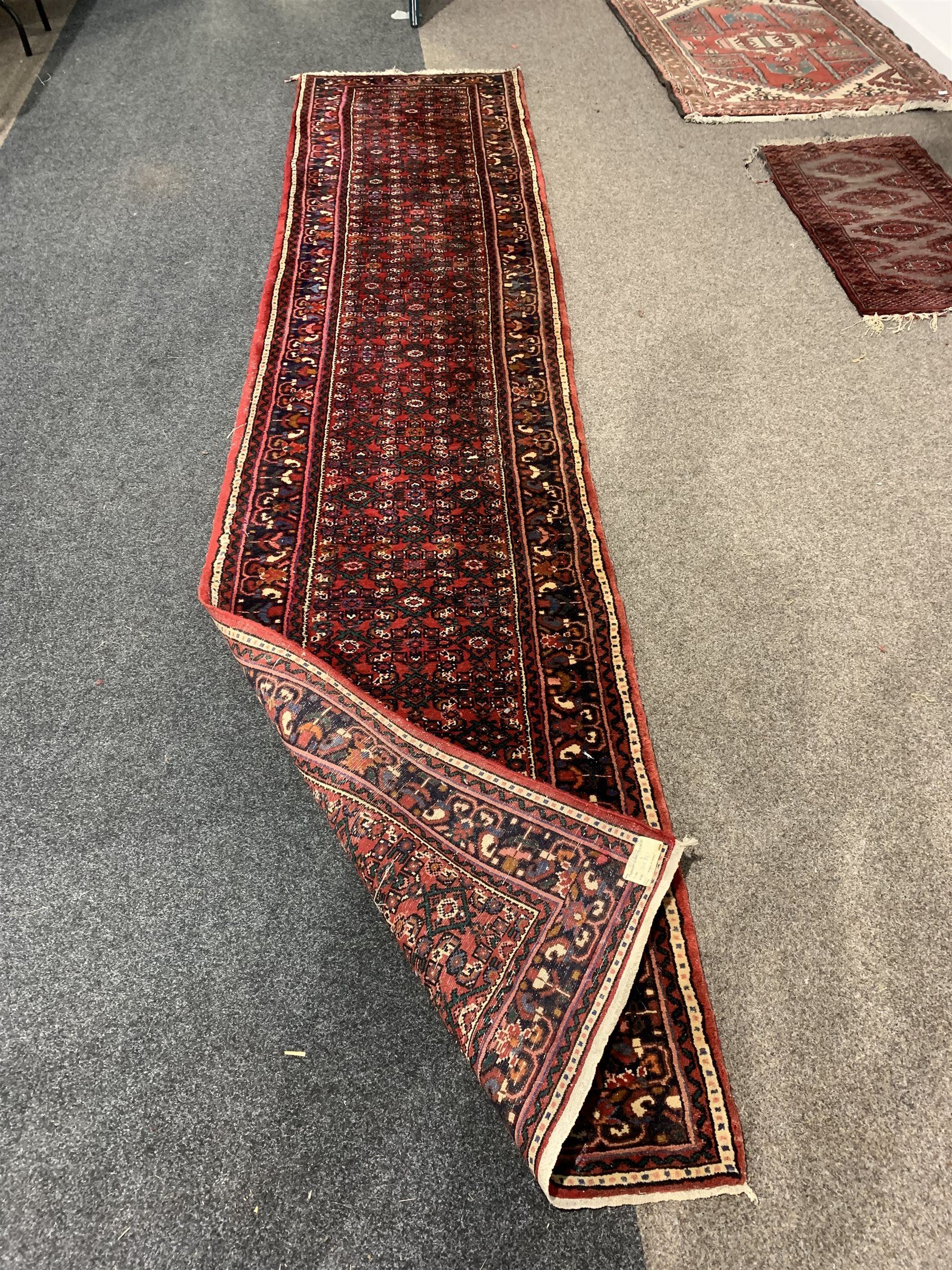 Central Asian runner rug, with repeating lozenge motif on busy red field, stylised foliate to border, 86cm x 400cm