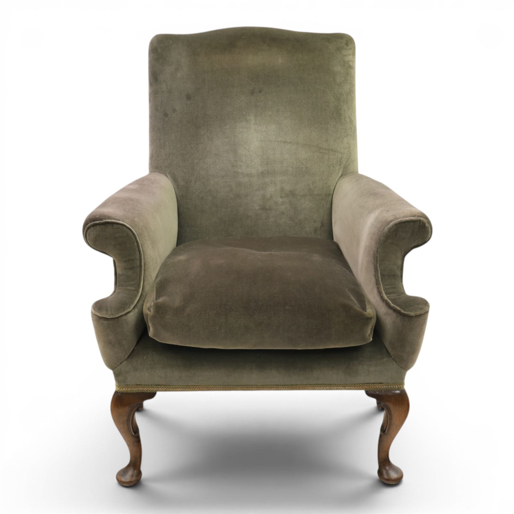 Pair of Georgian style wing armchairs, upholstered in green velvet, each with shaped wing backs, padded scroll arms and loose seat cushions, raised on cabriole supports terminating in pad feet, one with tasselled fringe