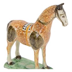 Late 18th/early 19th century Prattware pottery figure of a horse, possibly Yorkshire Potteries, circa 1790-1800, painted and sponge decorated in manganese, with blue spotted saddle secured with a yellow girth, upon a rectangular green base, H15.5cm