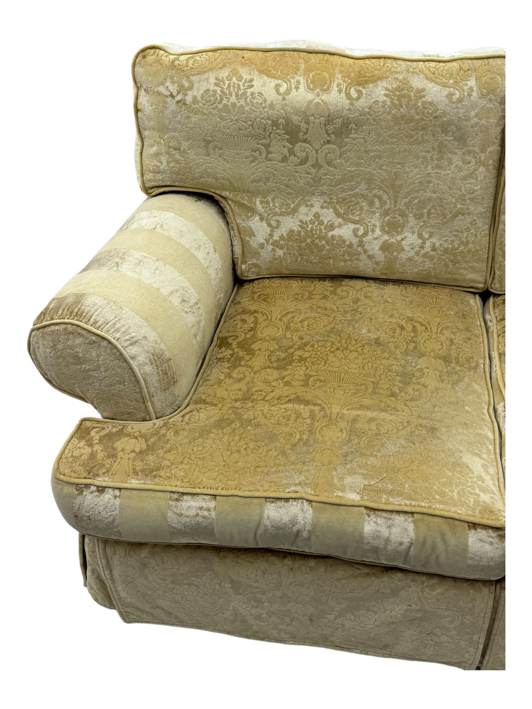 Contemporary two-seat sofa, upholstered in damask fabric with a pale gold floral pattern, rolled arms with covers, loose back and seat cushions, on matching skirted base with concealed castors