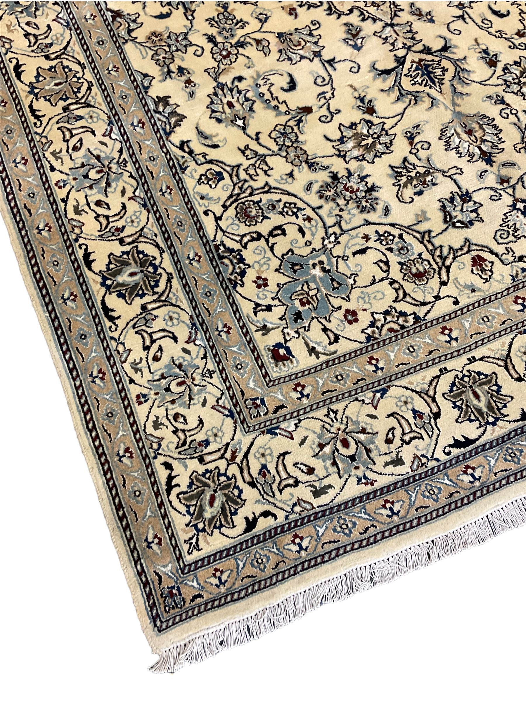 Central Persian Nain rug, wool with silk inlay, ivory ground decorated with scrolling and interlaced branch with stylised plant motifs, central floral medallion, triple band border with repeating design