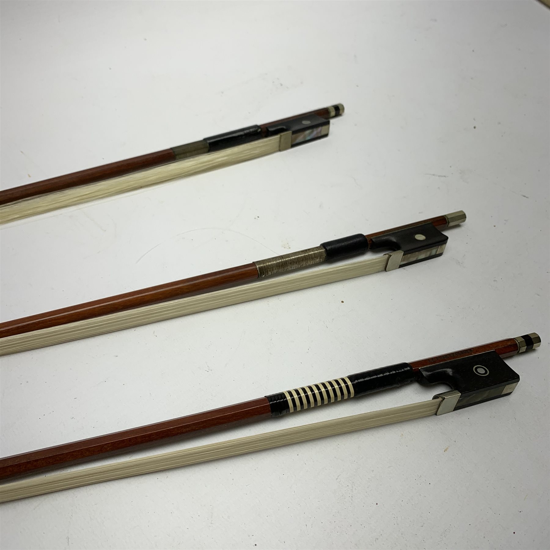 Three pernambuco bows by F.C. Pfretzschner with silver mounts, Adolf Thoma and Tourte