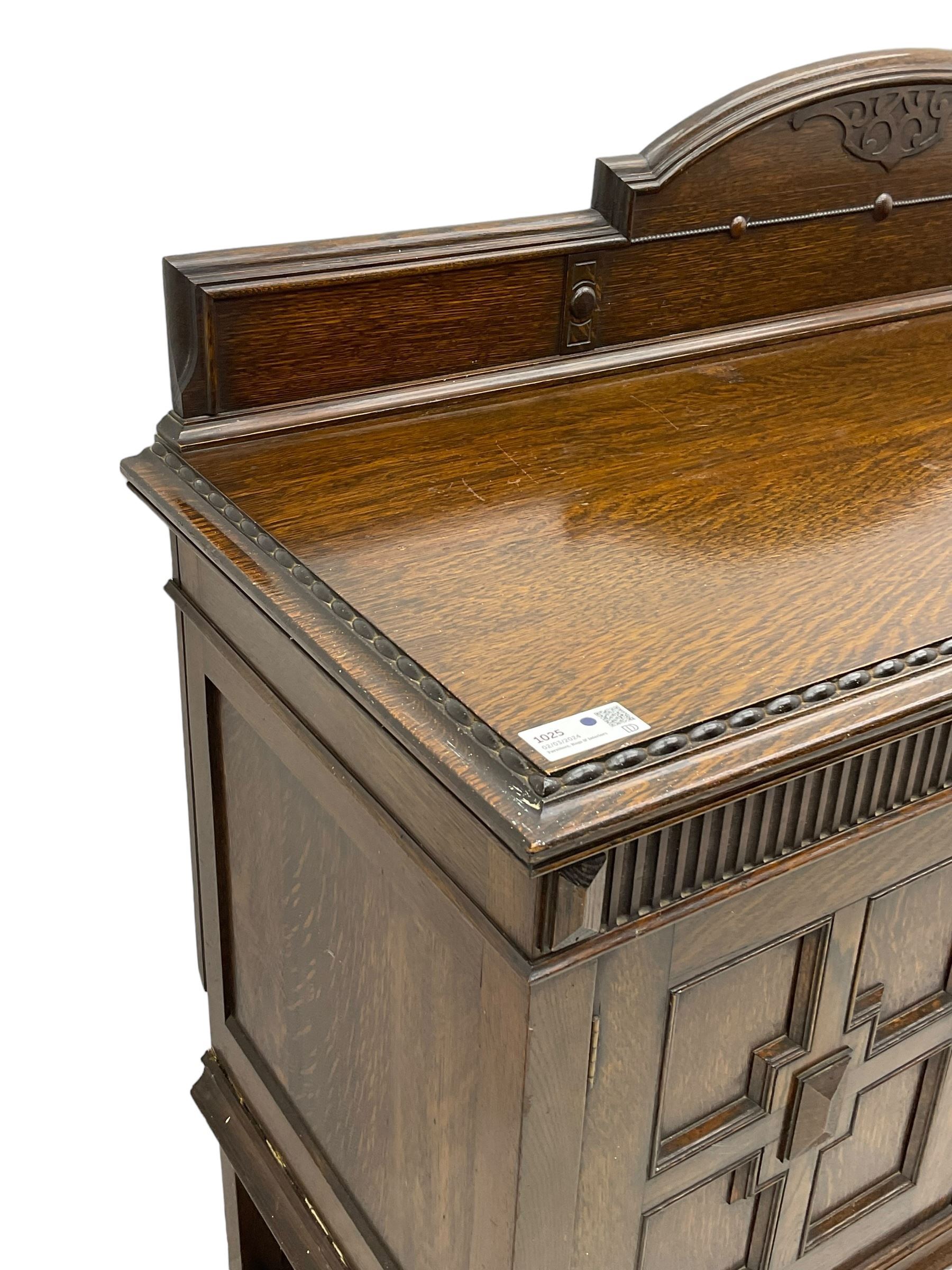 Early 20th century oak sideboard, raised stepped arch back over moulded rectangular top, fitted with two drawers and two panelled cupboards with geometric mouldings, on turned and lobe carved baluster feet united by stretchers 