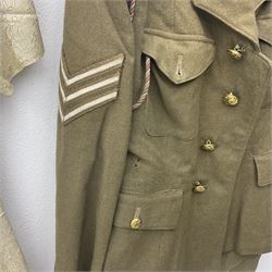 WW2 British female ATS Sergeant's service uniform grouping, consisting of four pocket female pattern service dress tunic with brass ATS shoulder titles and general service buttons; cloth lined interior with the original printed size label dated 1942; the matching khaki service dress skirt; and Greatcoat with size label dated 1945; together with army knitted sleeveless V-neck jumper; WRAC tunic, skirt and overcoat; full length cream and gold thread military evening dress by Hilliers Couture; and four webbing belts