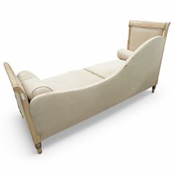 19th Century French day bed, the shaped back and scroll ends with fluted supports and carved rosettes, upholstered in natural linen with loose seat cushions and bolster pillows