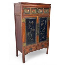 Late 19th century Chinese Qing dynasty red and black lacquered wood cabinet,  Fujianese province, upper cupboard enclosed by two doors with relief carved and gilt panels depicting figures behind glass, the large cupboard enclosed by two panelled doors carved with trailing foliate branches and birds, inscribed with Chinese characters, to the left ‘The red mountains are in the shape of Phoenixes and appear auspicious’ and to the right, ‘Wealth and honour are given by flowers and I hear the sound of the phoenix', fitted with two drawers, on square supports with carved brackets 