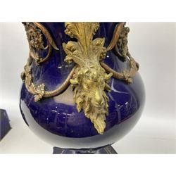 Pair of French large cobalt blue lidded urns, probably 19th century, the body decorated with ormolu ram's heads and ornate foliate design, the domed cover with brass berry finial, raised upon pedestal base with beaded decoration upon shaped plinth, H52cm