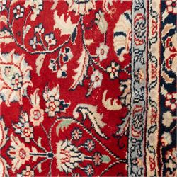 Persian crimson ground rug, interlacing floral stems linking ivory palmettes, rosettes and serrated leaves, within a navy floral border flanked by ivory patterned guards