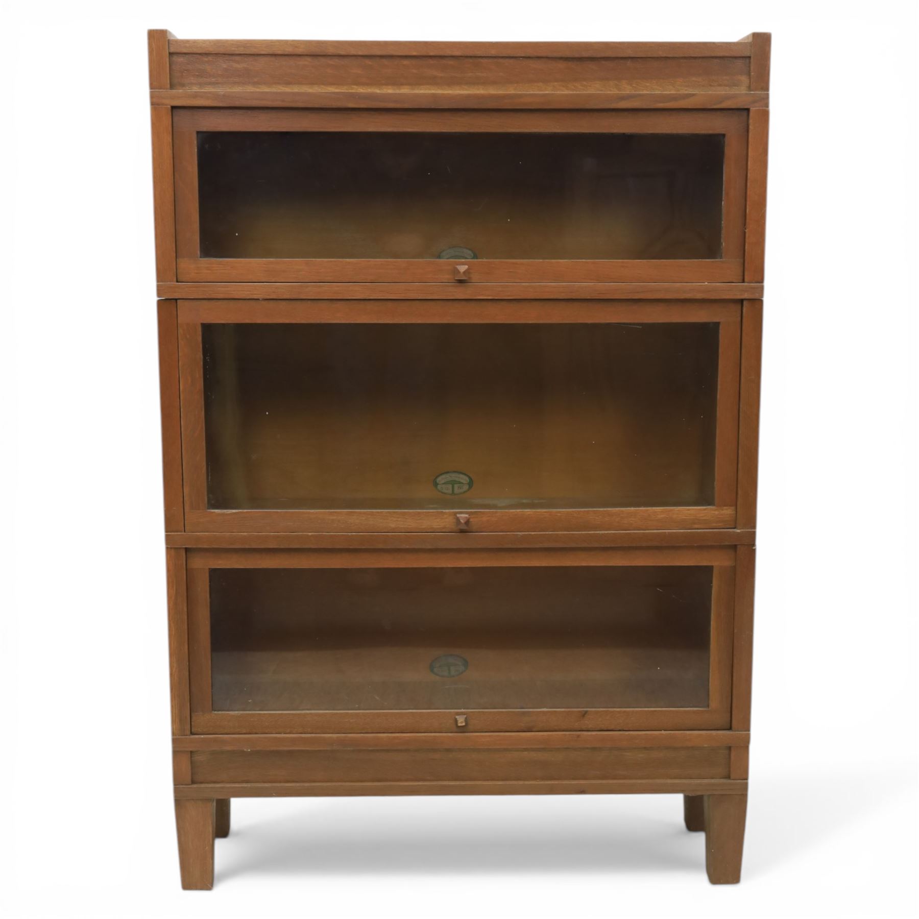 Globe Wernicke - Modular oak sectional bookcase, the three glazed up-and-over doors with panelled sides, raised on a plinth base with square supports
