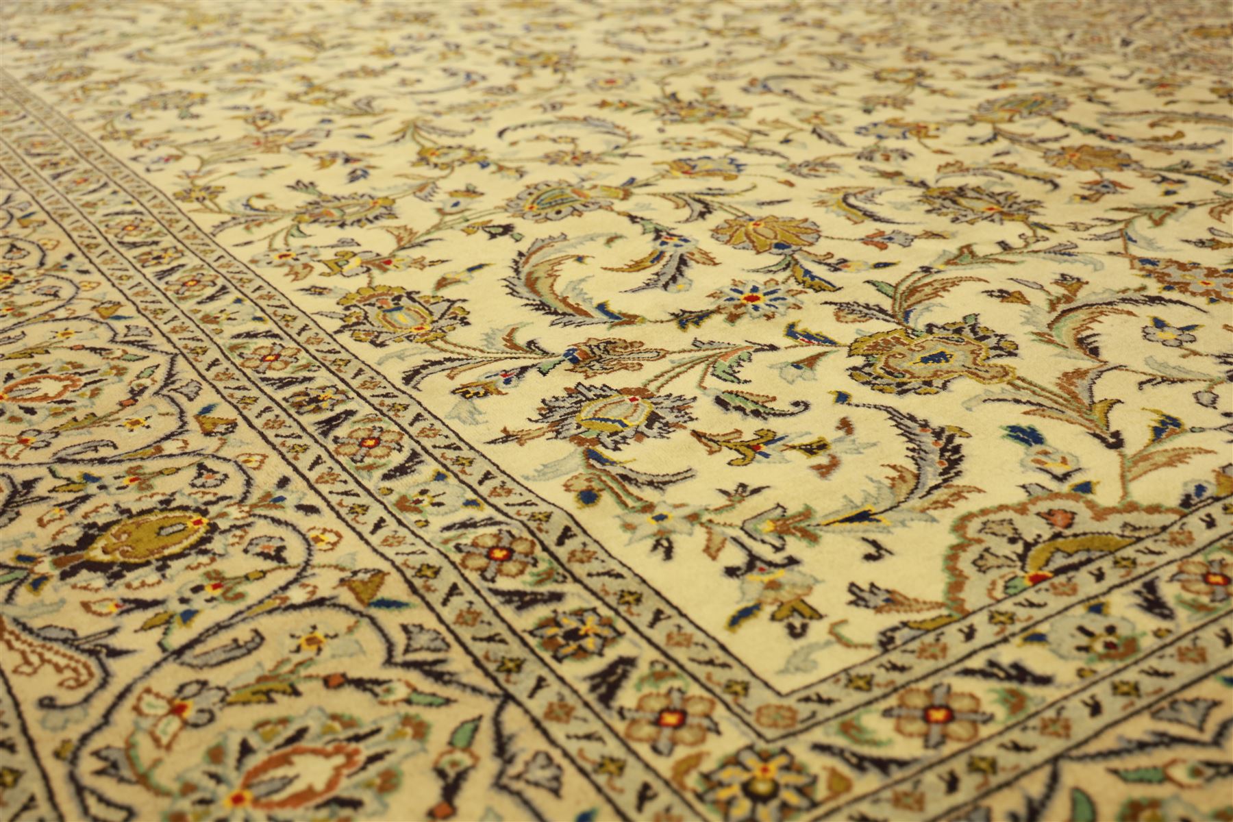 Central Persian Kashan carpet, ivory ground, field with an all-over design of scrolling palmettes and floral sprays in blue and terracotta within a beige ground and pale blue floral border