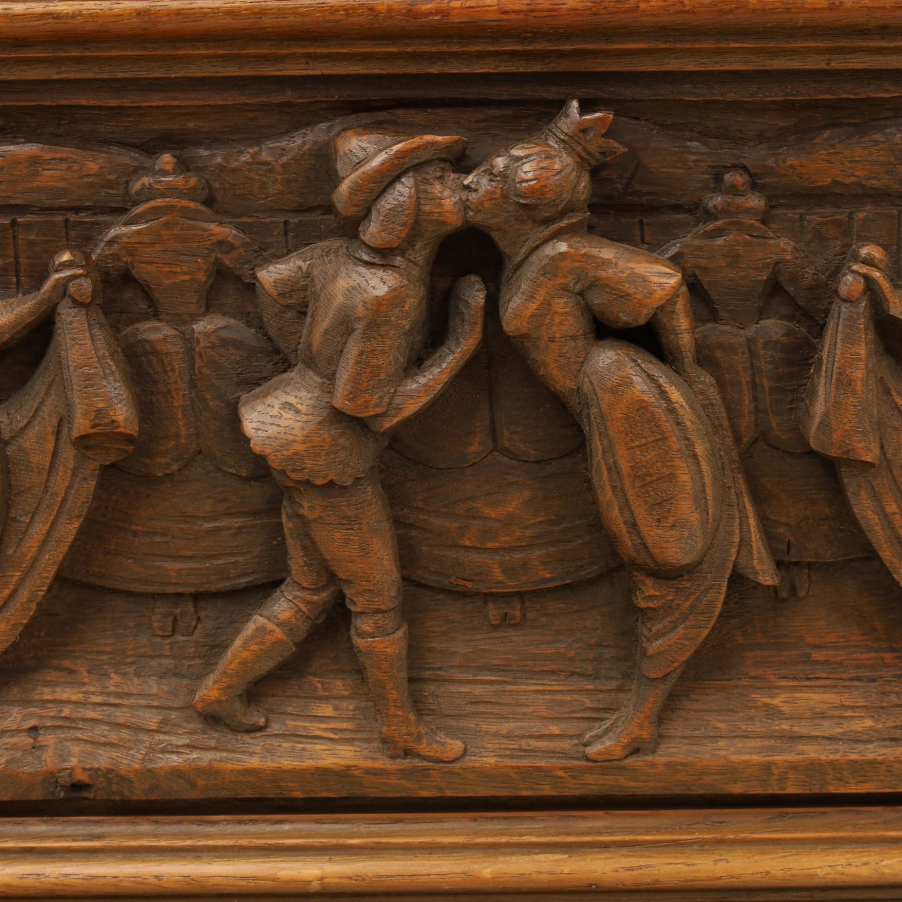 Carved oak coffer bench, rectangular moulded top above carved fall front, with figural, mask and foliate decoration, panelled sides, raised on turned bun feet with shaped lower apron
