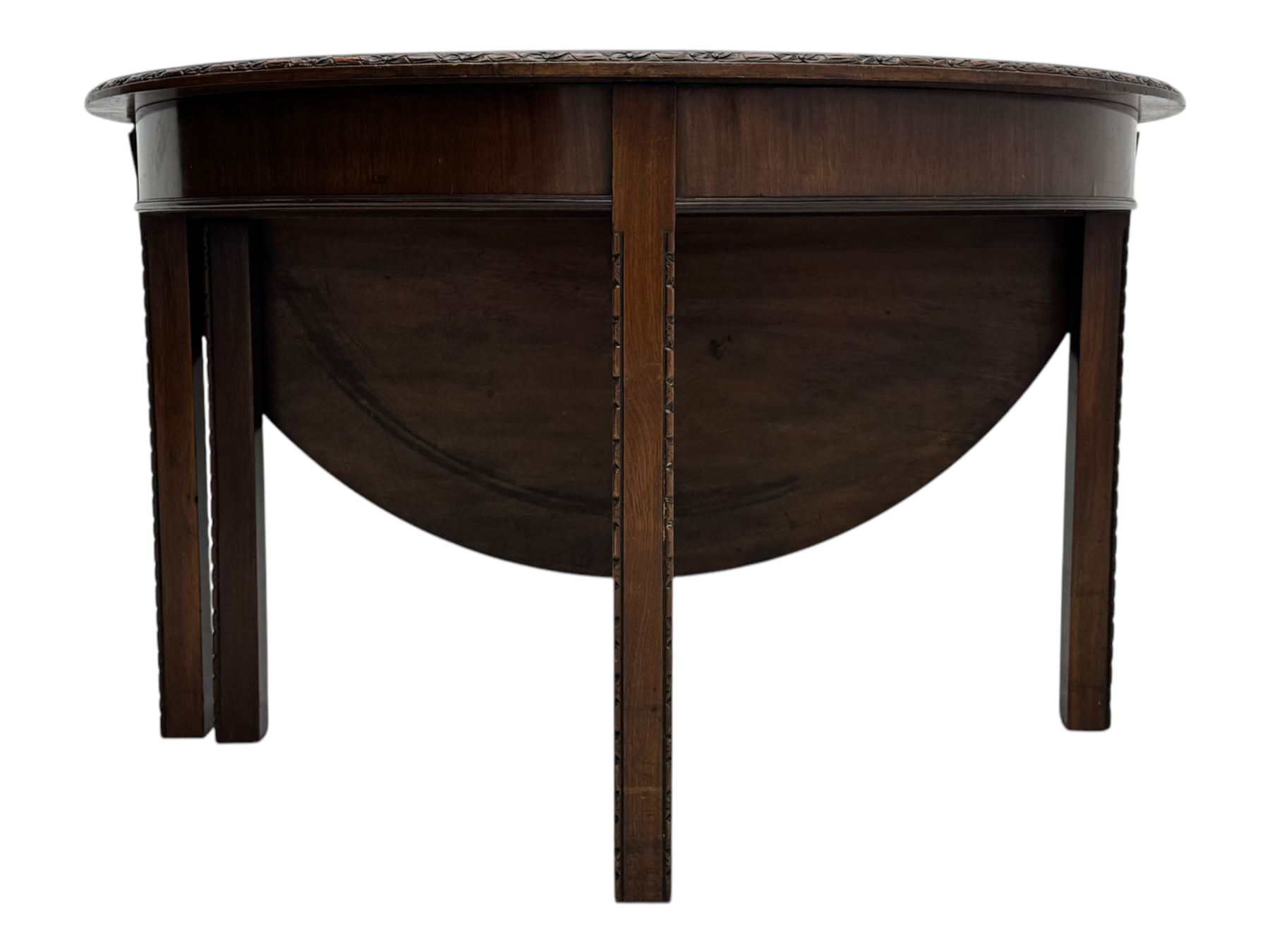 Early 20th century mahogany demi-lune table, the circular top with carved foliate border, raised on square section supports with relief carved edges