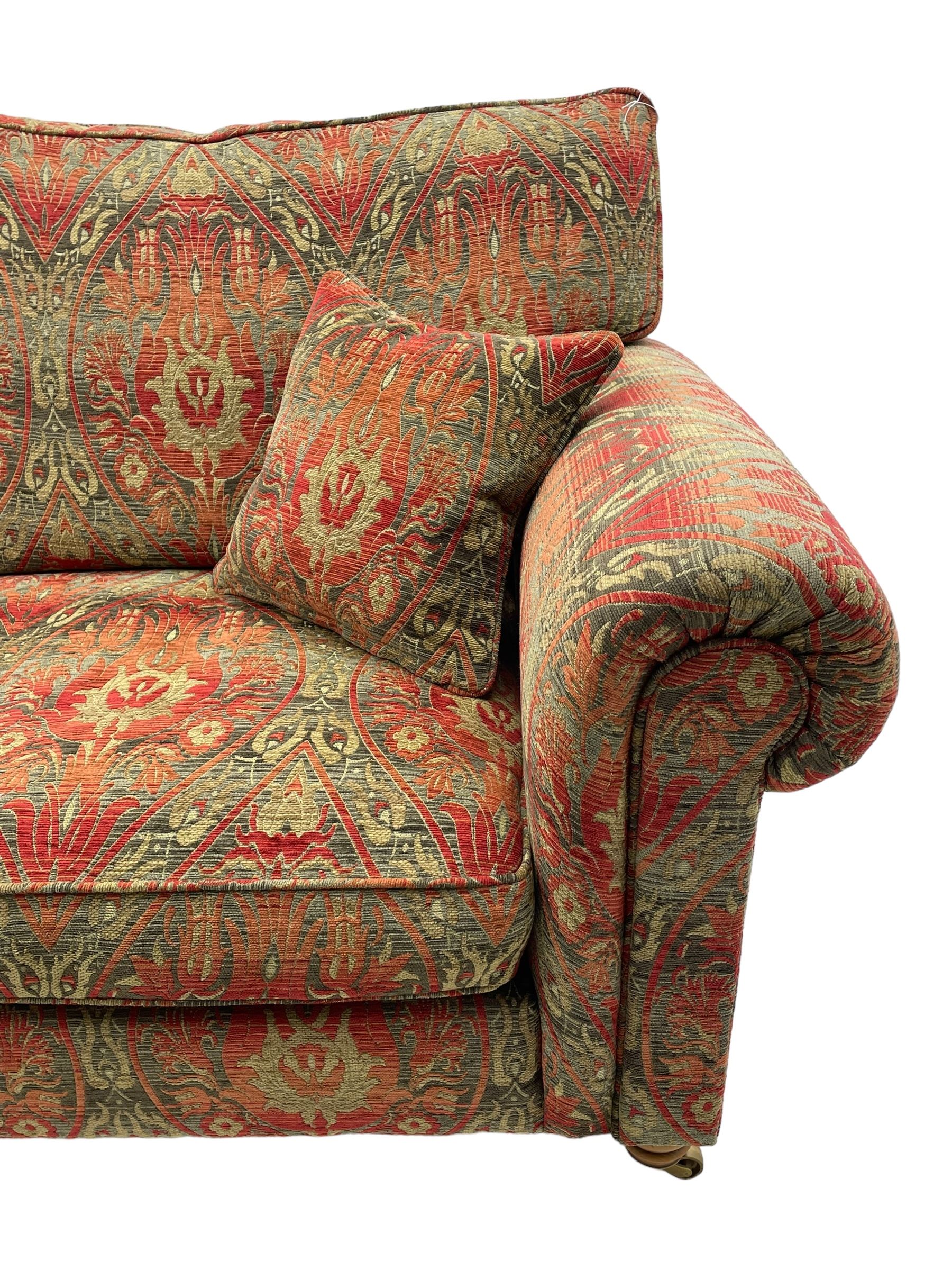 Duresta - 'Beaminster' grande two-seat sofa, traditional shape with rolled arms, upholstered in 'Althorp' russet and stone floral pattern fabric, on turned feet with brass castors
