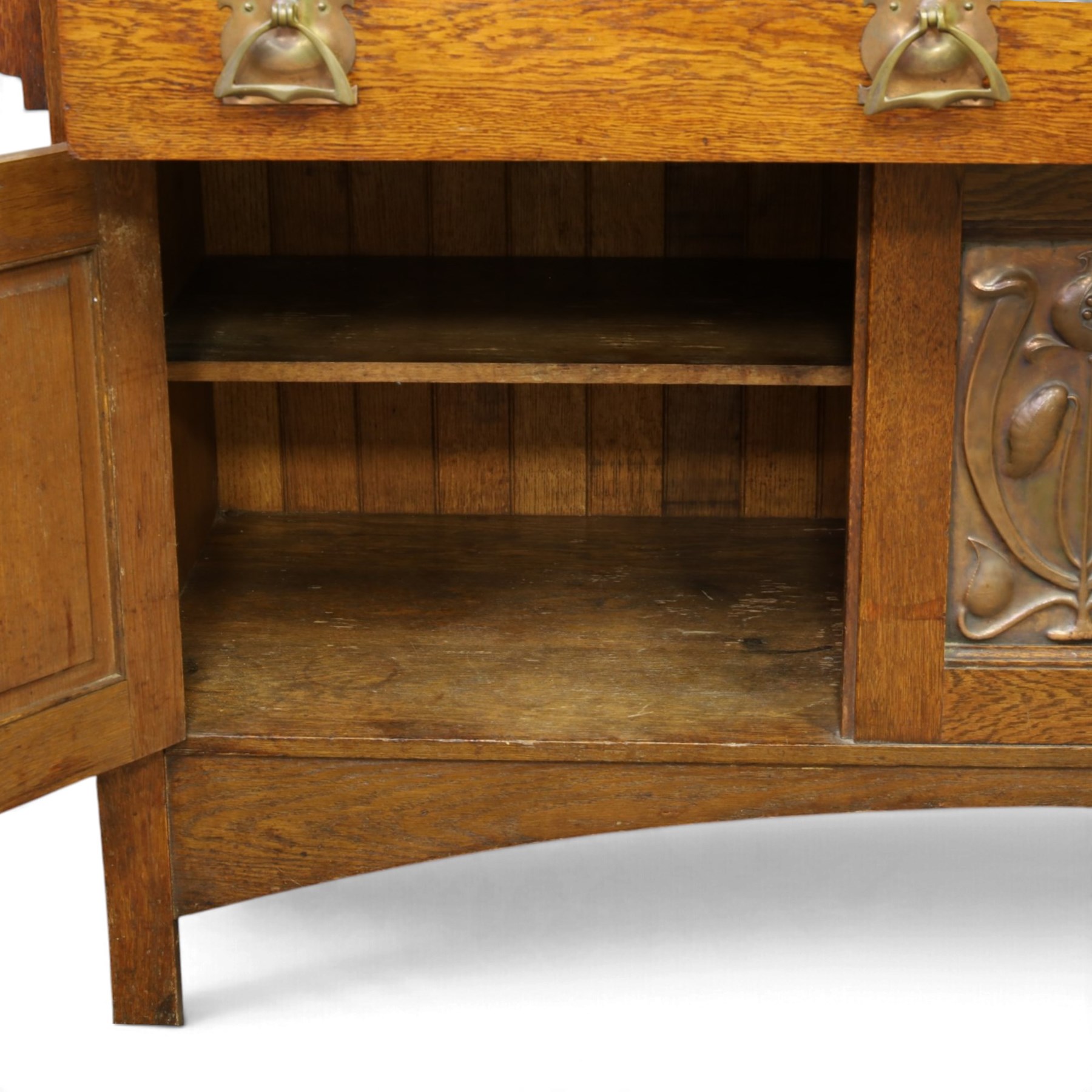 Art Nouveau oak mirrored sideboard, in the manner of Liberty's London, the raised back fitted with bevelled mirror plates divided by turned supports beneath a projecting cornice, above two drawers and panelled cupboard doors, the central panel applied with stylised floral carved panel, raised on shaped feet