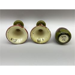 Minton Secessionist vase, with tube-lined stylised flower head decoration upon a red and green ground, printed mark to base 'Minton Ltd, No. 31', together with a matching pair of Minton Secessionist candle sticks, candlestick H17cm