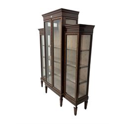 Late 19th century walnut and mahogany display cabinet, breakfront with carved dentil cornice, the friezes inlaid, fitted with four glazed doors surrounded by beading and crossbanding with further ebony inlay, three shelves fitted to the interior, raised on square tapering supports with spade feet