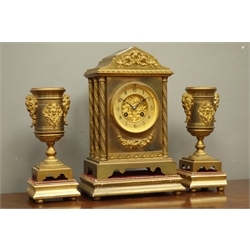  Late 19th century gilt metal architectural clock garniture, stepped pointed arch pediment, foliage twist column pilasters, mounted swags and flowers, pair urn garnitures, on moulded plinths with velvet tops, twin train movement striking the hours and half on coil, H33cm  