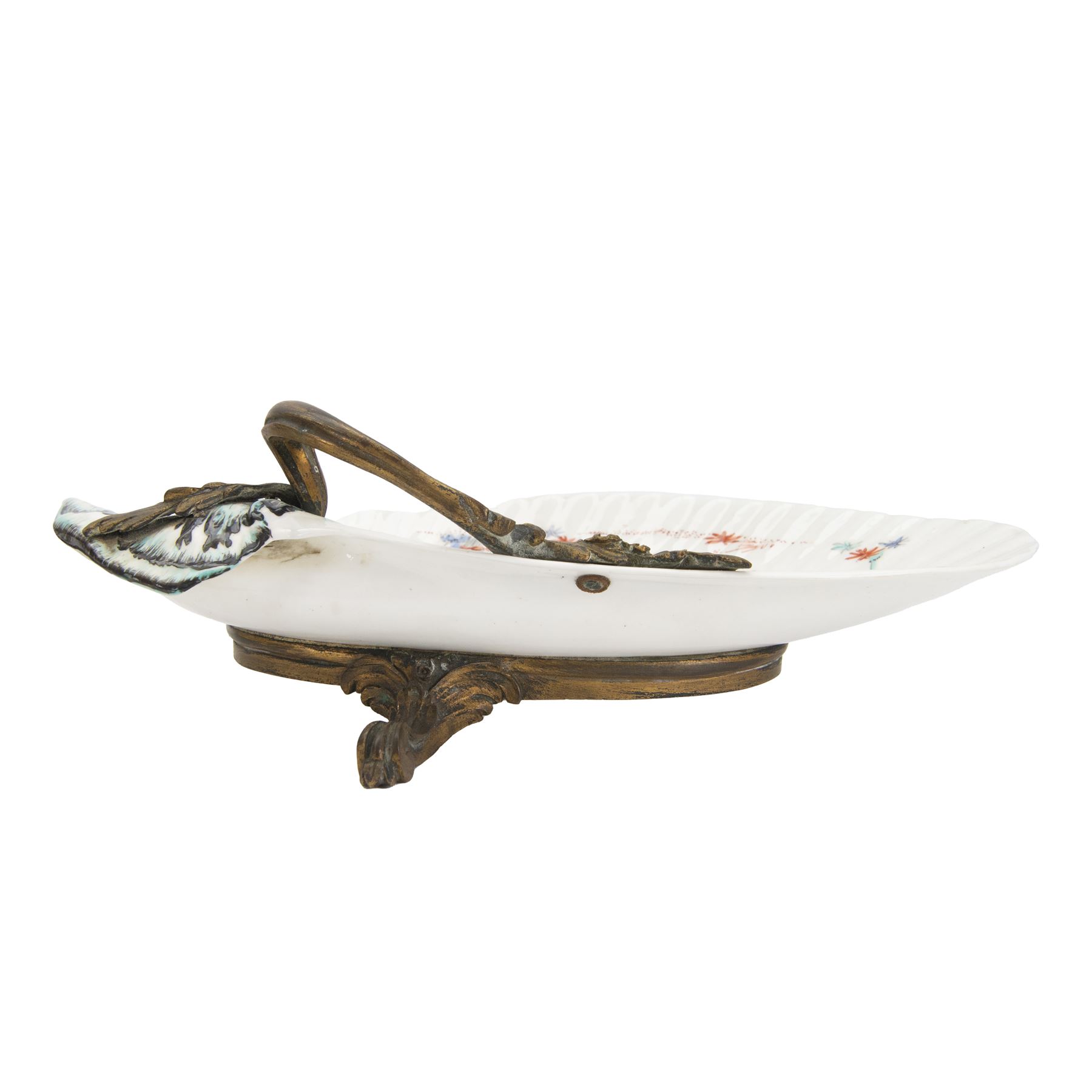 18th century porcelain dish, attributed to Chantilly, circa 1740-1750, with later ormolu mounted handle and feet, the dish of moulded shell form, painted in the Kakiemon pallet with an exotic bird and grasshopper amidst flowers and foliage, with foliate ormolu handle, and upon three scrolling foliate feet, possible obscure Chantilly mark beneath, including handle H10cm W31cm

A letter from the Ashmolean Museum accompanied the dish when it entered the current vendor's family collection. In the letter, Dr. Impey noted that the painting is European, possibly Dutch. The general consensus was that the shell dates to the 18th century, with the ormolu mounts likely added in the 19th century. However, the factory of origin remained unidentified. The letter was signed by Ian Lowe in 1974. Further consultation at the time with four members of staff at the Victoria and Albert Museum yielded differing opinions, with suggestions including Chantilly and Bow. The piece has been attributed to Chantilly partly due to what appears to be a partially obliterated horn motif beneath.